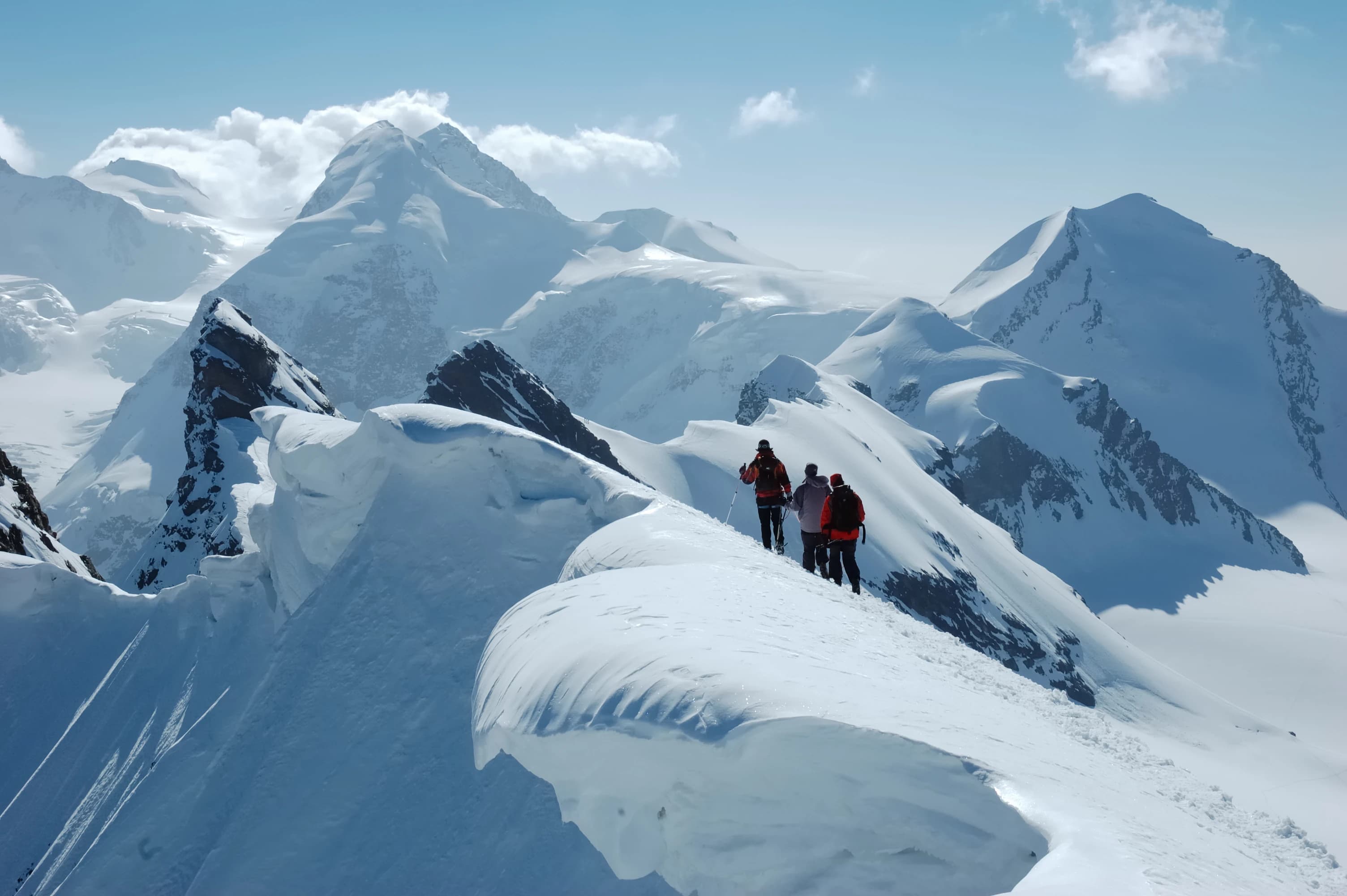Dramatische Weitwinkel-Aufnahme einer Wandergruppe beim Erreichen eines alpinen Gipfels
